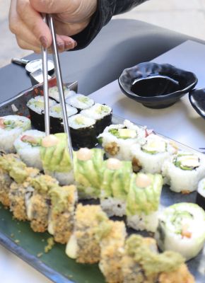palillos cogiendo una pieza de sushi de una tabla de sushi